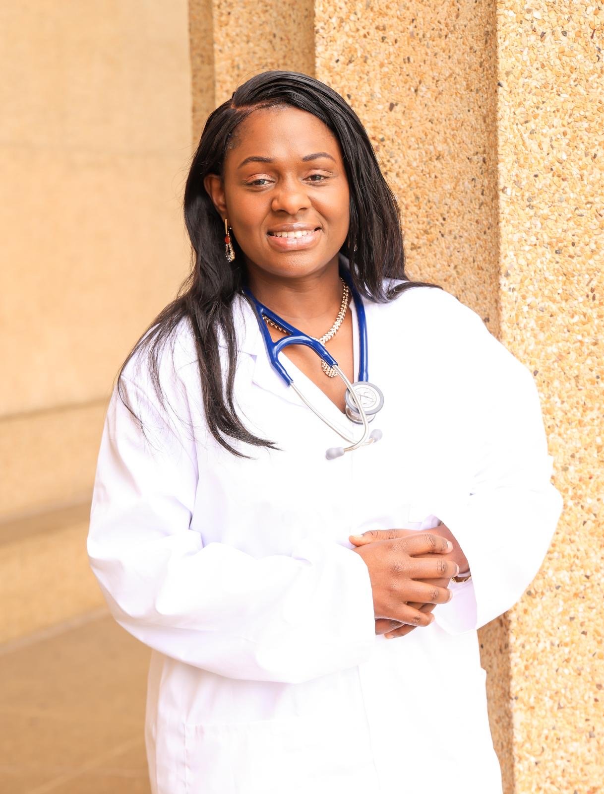 Smiling female healthcare professional wearing a white coat and stethoscope outdoors.